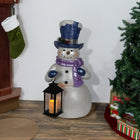 Alpine Corporation SKY562HH-S-TM Lavender Winter Snowman Holding Lantern Statue with Flashing Warm White LED Candle, 14” Tall, Indoor/Outdoor Holiday Decoration